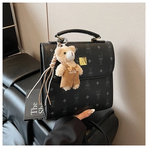 Détail du sac bandoulière vintage noir à motifs avec un joli porte-clés en peluche ours