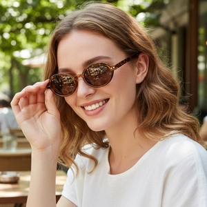 Chic oval tortoiseshell sunglasses with brown lenses worn by a model in outdoor sunlight