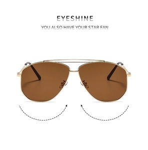 Detail of pilot sunglasses featuring a gold metal double bridge and dark brown lenses