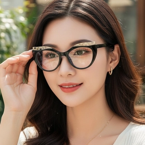 Chic black cat-eye glasses with gold hollow lace metal trim on a female model