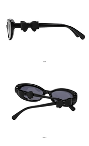 Détail de lunettes de soleil Y2K noires avec nœuds 3D latéraux et verres foncés