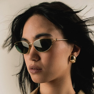 Retro cat-eye sunglasses with gold metal frame and dark lenses worn by a model