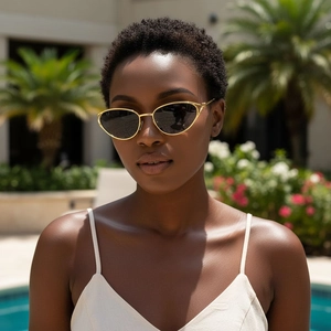 Fashionable gold oval cat-eye sunglasses with dark lenses worn by a model at a sunny pool