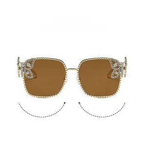 Detail of luxury gold metal frame sunglasses with crystal butterfly accents and brown lenses