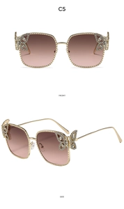 Close-up of square gold sunglasses with rhinestone butterfly hinges and gradient lenses