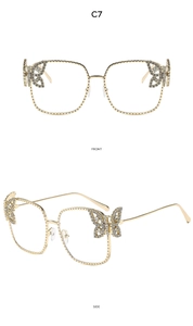 Detail view of gold square metal frame sunglasses with crystal butterfly ornaments and clear lenses