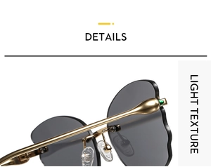 Detail of rimless sunglasses with wave-cut dark grey lenses and golden metal temples