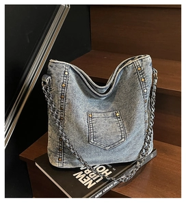 Detail of vintage blue denim bag featuring metal rivets and textured washing effect