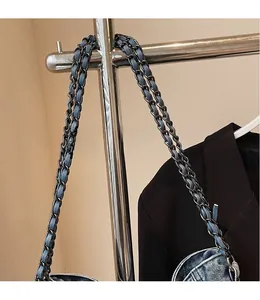 Detail of woven chain and denim strap on blue washed denim crossbody bag