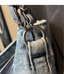 Detail of light blue denim fabric with distressed edges and gunmetal chain strap