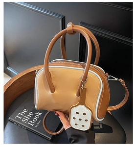 Detalle del bolso bowling retro de cuero con ribete azul y colgante en forma de raqueta