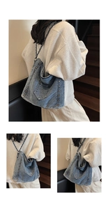 Detail view of denim shoulder bag featuring brass rivets and black metal chain strap