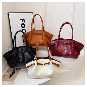 Various crocodile pattern wing bags in black, burgundy and orange displayed on steps