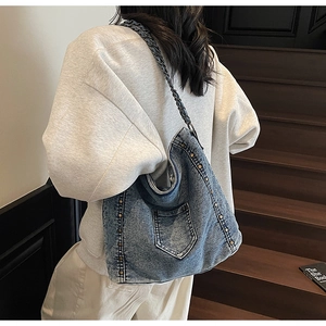 Detail of vintage denim hobo bag with metal rivets and leather chain shoulder strap
