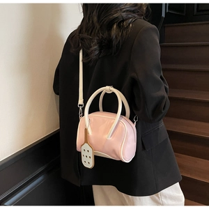 Pink and white bowling shoulder bag with adjustable strap shown on a wooden staircase