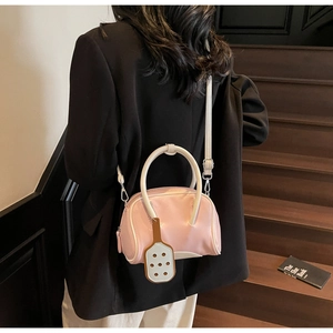 Pink Boston style handbag with white handles and shoulder strap shown on wood stairs