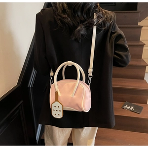 Detail of light pink contrast color pillow bag with white handles and detachable strap