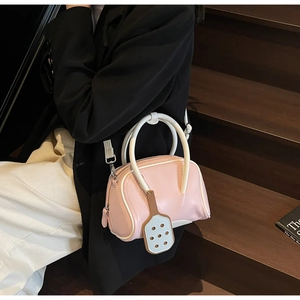Close-up of pink glossy bowling bag with contrast trim and racket-shaped pendant on stairs