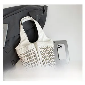 Detail of white studded tote bag with silver rivets and front pockets on grey blazer