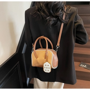 Detail of macaron bicolor shoulder bag in yellow and brown leather with racket charm