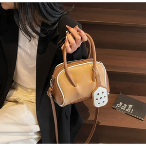 Detail of a brown and light blue leather bowling handbag with handle and shoulder strap