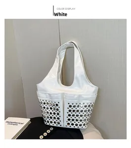 Detail of white patent leather bucket bag featuring silver rivet studs and large front pockets