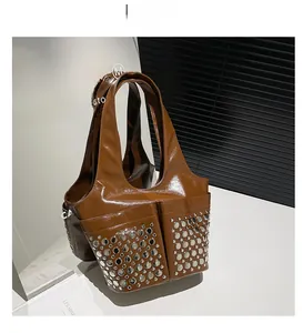 Detail of brown glossy patent leather tote with silver rivets and side pocket