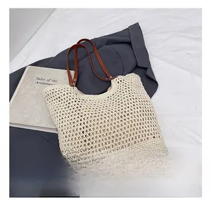 Detailed close-up of hollow crochet knit texture and brown leather strap on cream tote