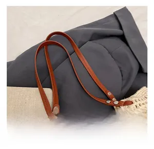 Detail of hollow woven shoulder bag featuring brown leather handles and metal rivets