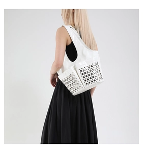 Detail of white tote bag with silver metal studs and double front pockets on model