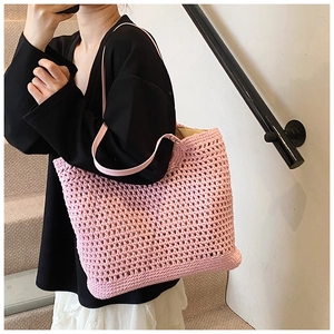Detailed close-up of light pink crochet tote bag texture with slim leather shoulder straps