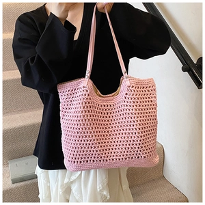 Close-up of pink woven hollow-out beach tote with leather handles on a shoulder bag
