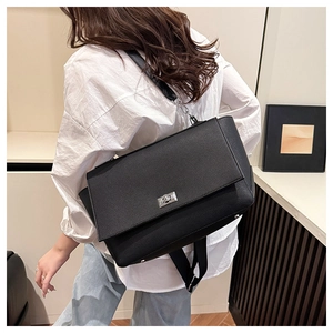 Detail view of black lychee-textured crossbody bag with silver twist lock on a model