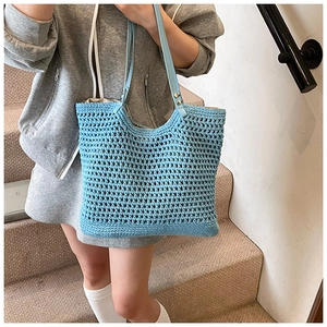 Close-up of the hollow blue crochet tote bag featuring light blue faux leather straps