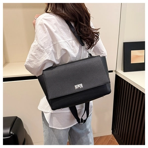 Side view of black lychee leather tote bag with silver metal twist lock worn by model
