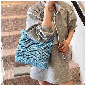 Sky blue knit tote bag with hollow mesh design being carried by a model on stairs