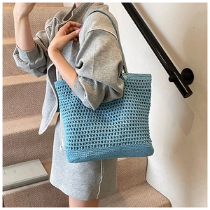 Detail of light blue woven tote bag showing honeycombed crochet pattern and leather straps