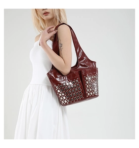 Close-up of wine red bucket bag featuring glossy finish and silver stud embellishments