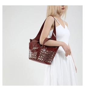 Detailed view of dark red shoulder bag featuring silver rivets on glossy leather surface