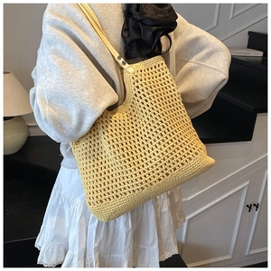 Detail of light yellow woven tote bag featuring mesh texture and white leather shoulder strap