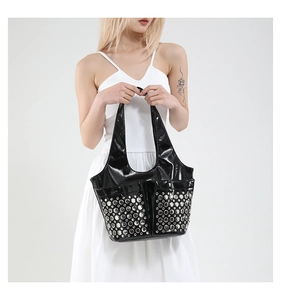 Close-up of black patent leather tote bag with metallic rivet eyelets decoration