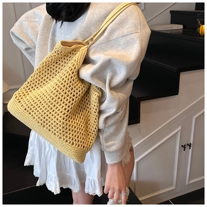 Close-up of bright yellow woven tote bag with intricate mesh pattern and sturdy handles