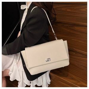 Detail view of cream textured leather square bag with silver twist lock on a model
