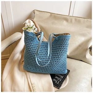 Blue hollow out crochet tote bag with leather straps on armchair for summer vacation