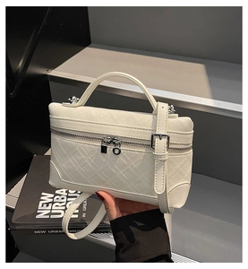 Close-up of white quilted leather texture on a stylish handbag with silver dual zippers
