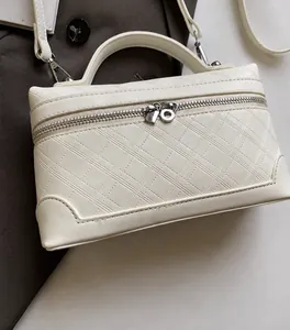 Detail of cream crossbody bag featuring diamond quilted stitching and top handle