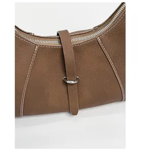 Detail of caramel lychee leather shoulder bag with white stitching and silver hardware