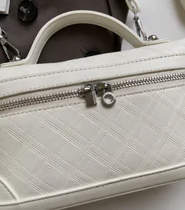 Detail of white quilted handbag with smooth dual silver zippers and premium hardware