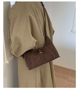Detail of dark brown retro crescent bag with white stitching and metal buckle closure