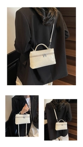 Close-up of white quilted leather texture and silver zipper hardware on mini tote bag